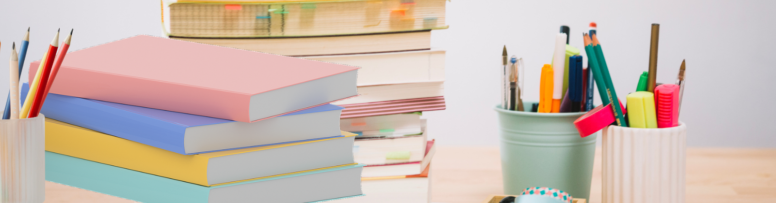 stack of books and notebooks on desk, three cups of pens and pencils on desk, colorful stack of notebooks
